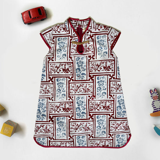 Flat lay of traditional white, red, blue cheongsam for girls with a gold Chinese knot button and red trimmings