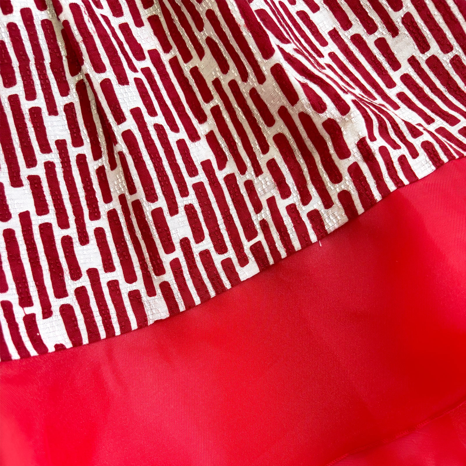 Close up of the details of a plain red lining on the bottom of a batik skirt