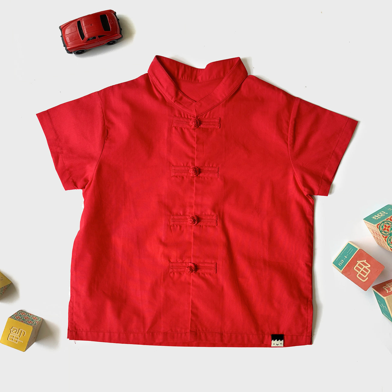 Flat lay of a plain red boys cheongsam shirt for Chinese New Year