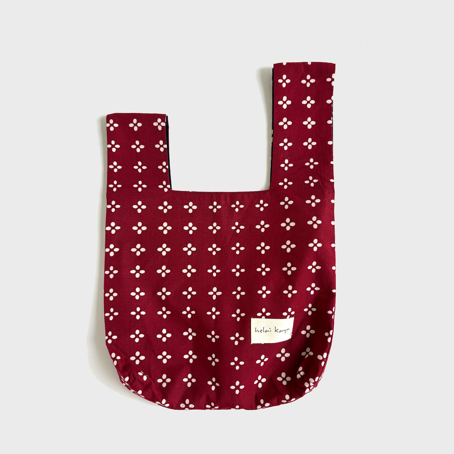 Red batik fabric bag with white floral pattern on a light gray background