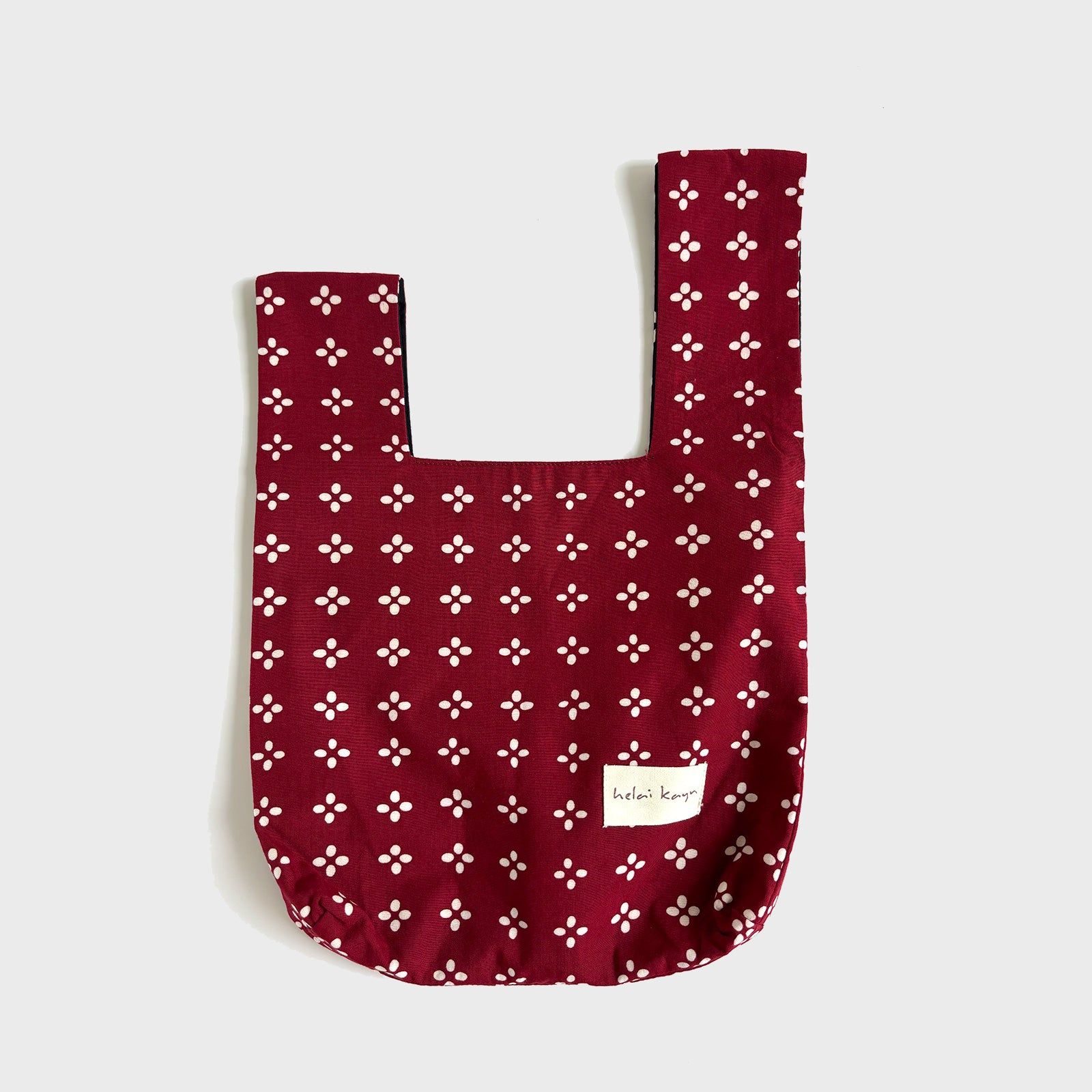 Red batik fabric bag with white floral pattern on a light gray background