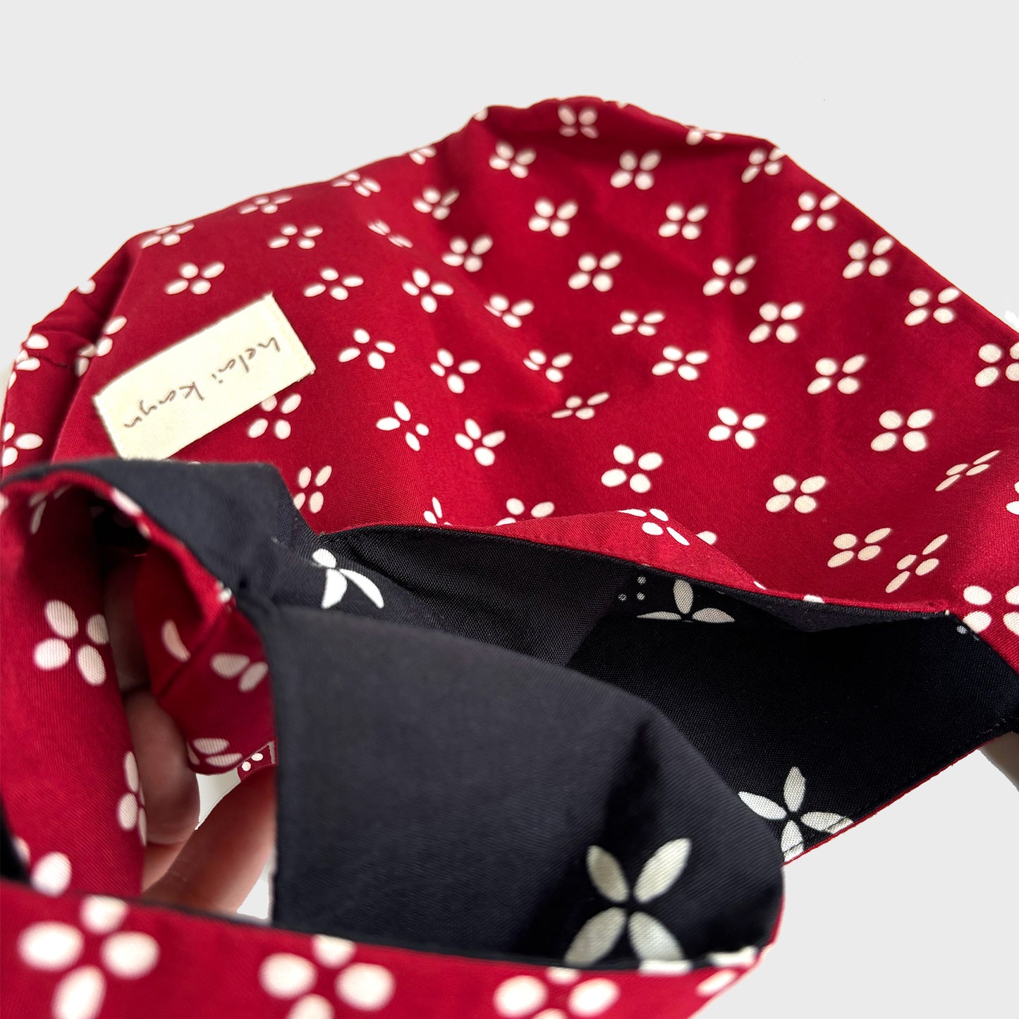 Reversible Red batik fabric bag with  with white floral pattern showing inner black fabric on a light gray background