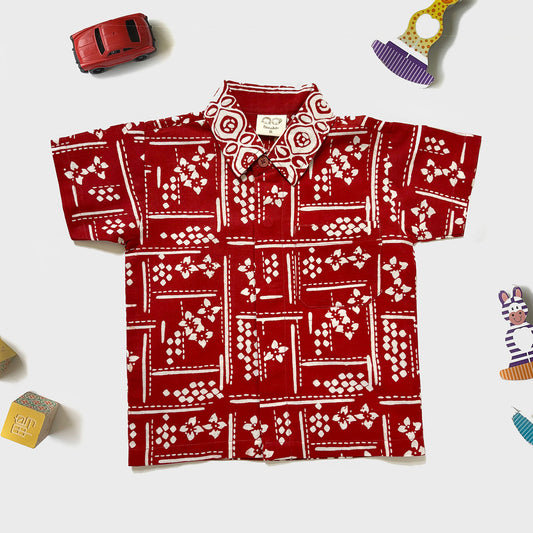 Modern batik boys shirt in orange red with flowers and geometric patterns.