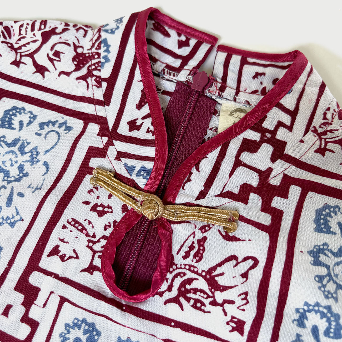 Close up of mandarin collar with gold Chinese knot collar. Red zipper of the dress.