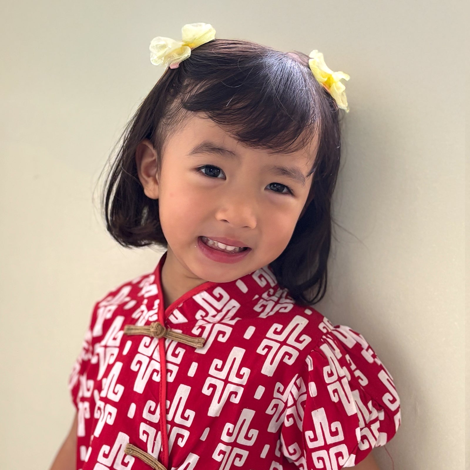 Girl smiling wearing a red batik cheongsam in an ikat print