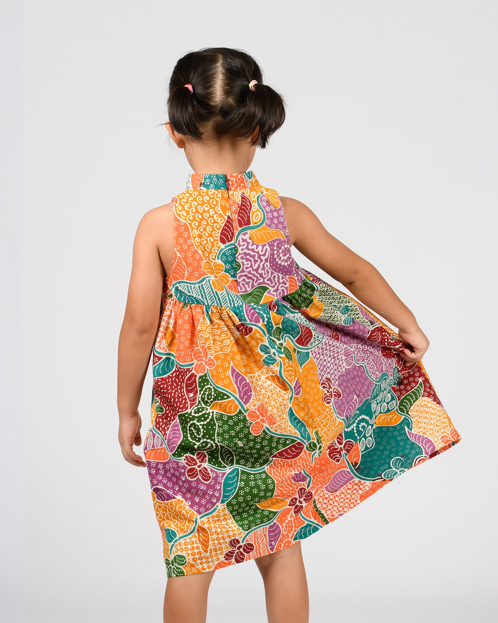 Child wearing a colorful patterned dress on a white background