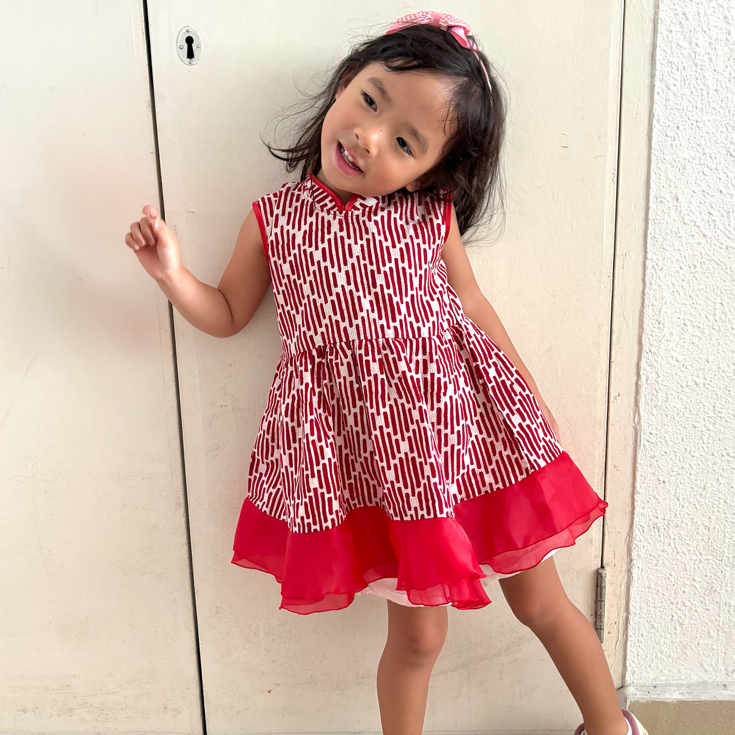 Girl wearing a red and white batik dress with a mandarin collar
