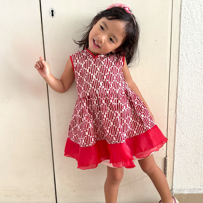 Girl wearing a red and white batik dress with a mandarin collar