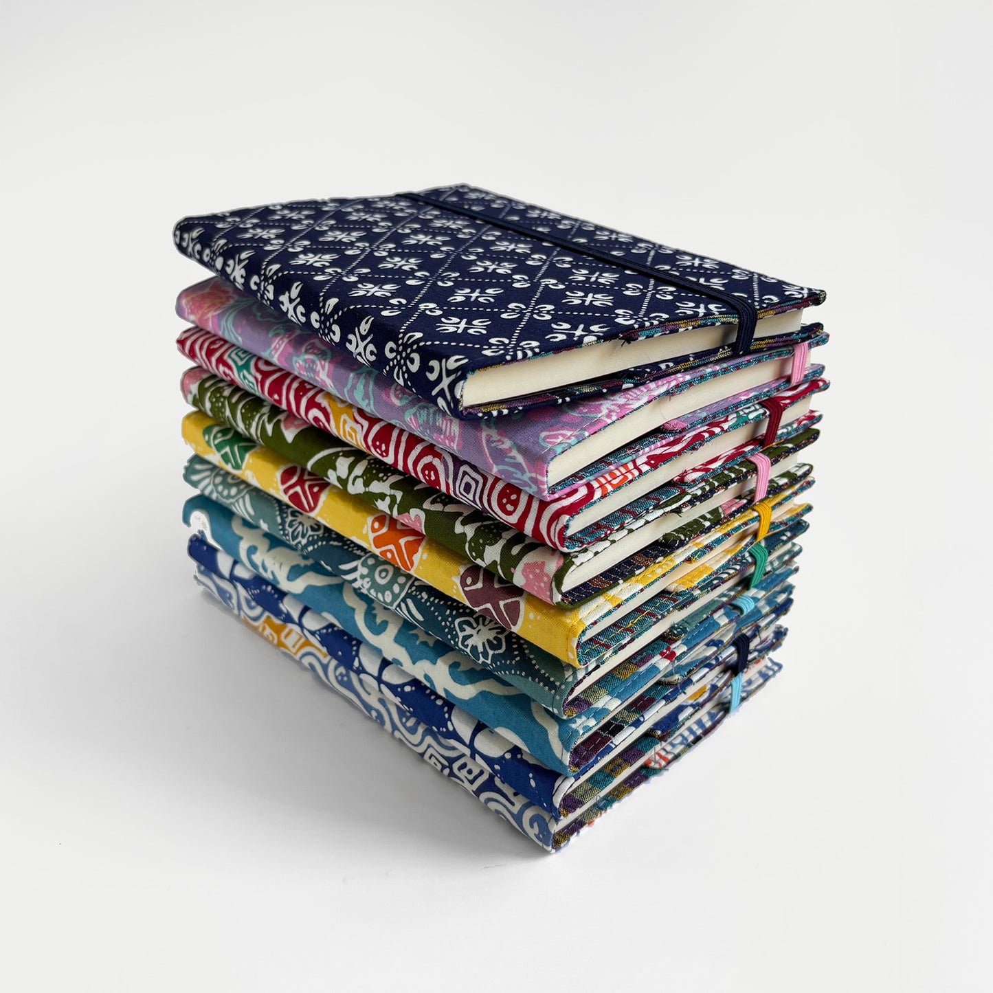 Stack of colorful patterned notebooks on a white background