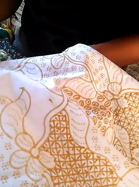 Close-up of a fabric with intricate wax patterns on a white background